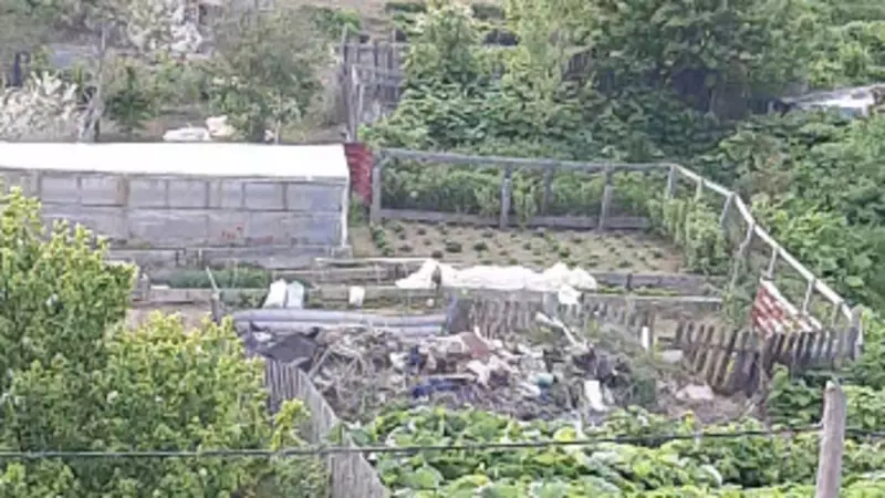 Зловонная свалка выросла за забором жилого дома в Холмске