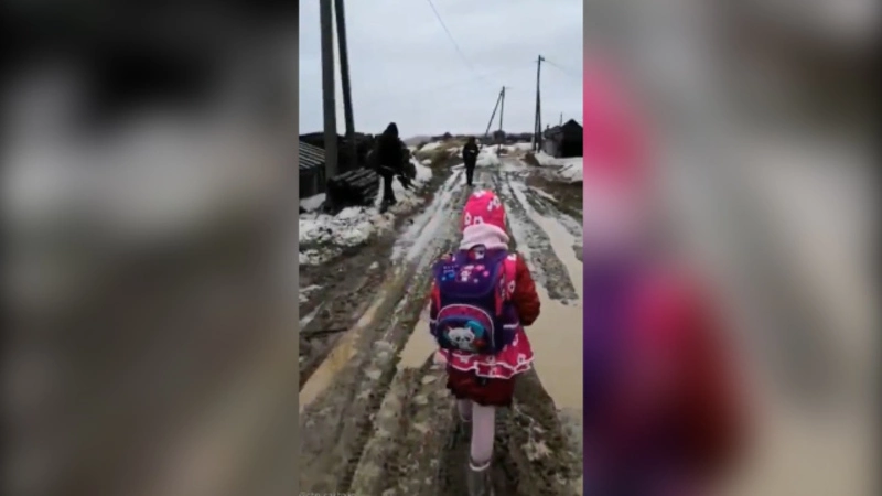 Дети Томари месят грязь по дороге в школу. Родители переносят их на руках