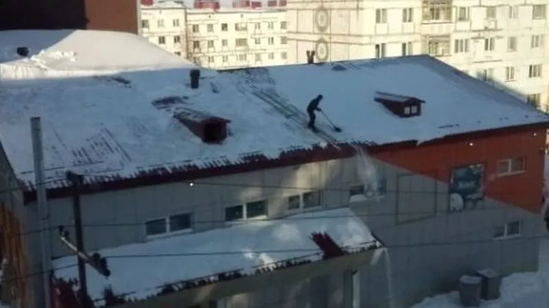 В Охе мужчина без страховки сваливал груды снега с крыши торгового центра