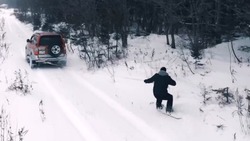 Автомобиль протащил мужчину на сноуборде по заснеженной дороге в Корсакове